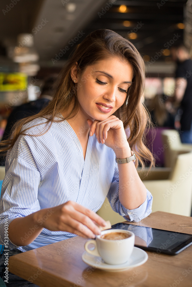 Young woman in cafe using tablet and drinking coffee Young woman in cafe using tablet and drinking coffee