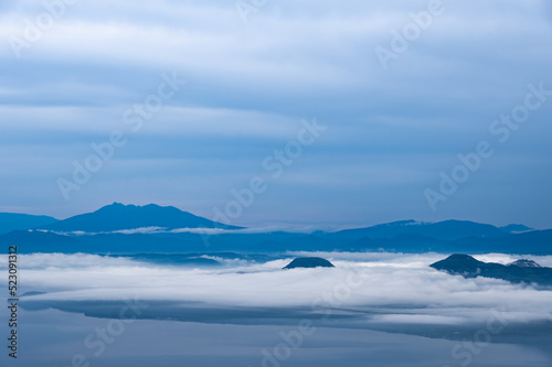 曇り空の下靄の流れる地上を見下ろす風景。日本の北海道の津別峠で。