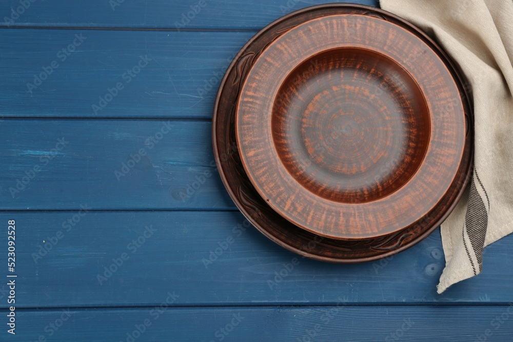 Clay plates on blue wooden table, flat lay. Space for text Clay plates on blue wooden table, flat lay. Space for text