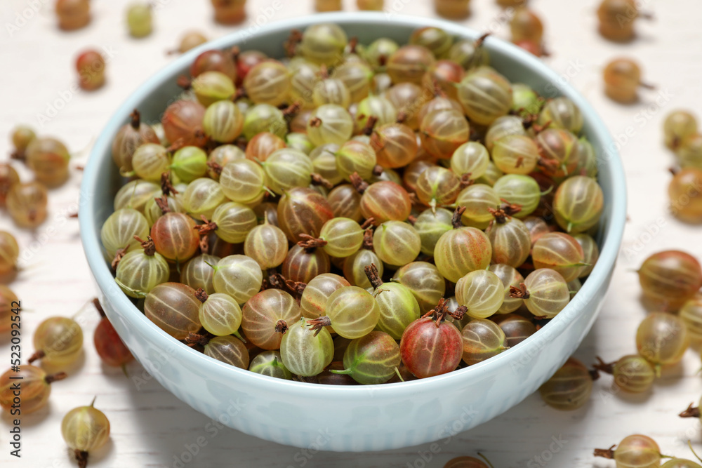 Bowl with fresh ripe gooseberries on white table, closeup Bowl with fresh ripe gooseberries on white table, closeup