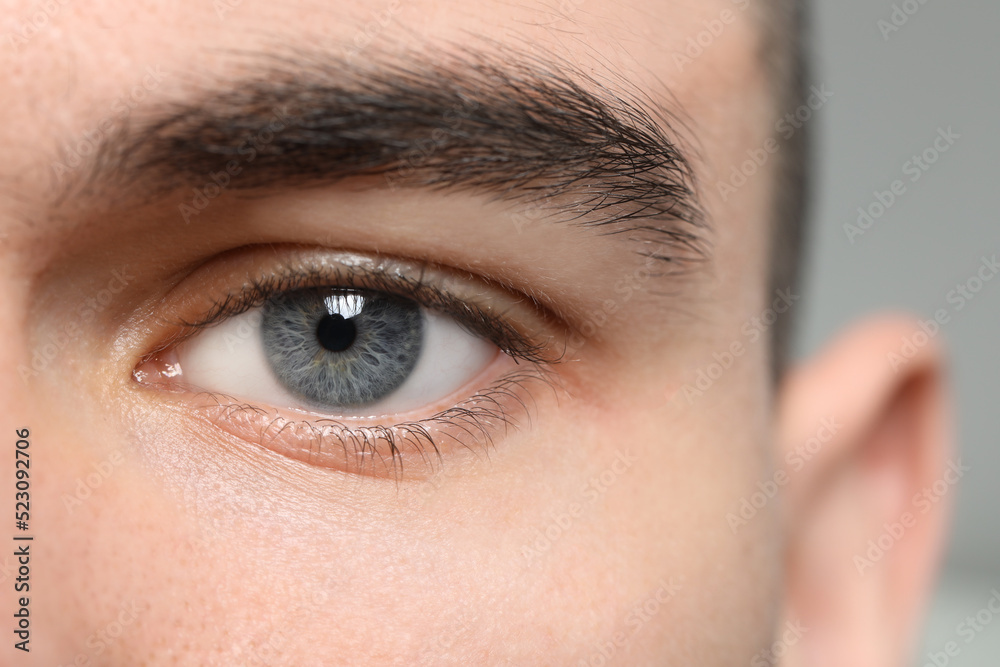 Fototapeta premium Closeup view of young man with beautiful grey eyes on blurred background