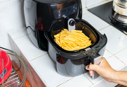 Woman hand is holding the tray of the oil free fryer machine.