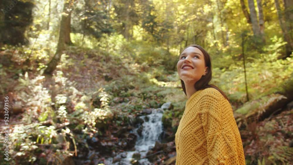 Young ginger women in front of beautiful colorful landscape with stream and forest in autumn colors Young ginger women in front of beautiful colorful landscape with stream and forest in autumn colors