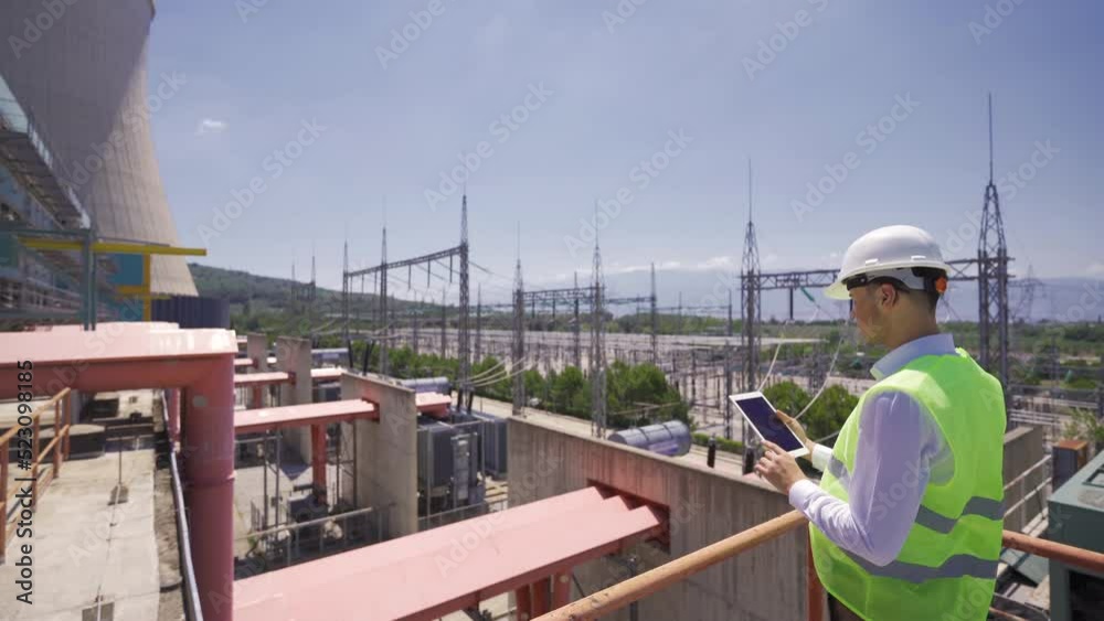 Engineer supervising a nuclear power plant.
The engineer continues by working with his tablet examining the plant.
