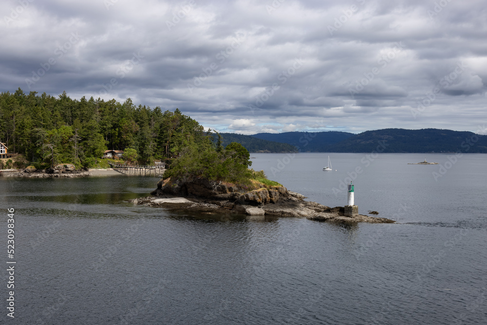 Treed Island with Homes, boats and docks, nearby smaller island with lighthouse. Summer Season. Gulf Islands near Vancouver Island, British Columbia, Canada. Canadian Landscape.