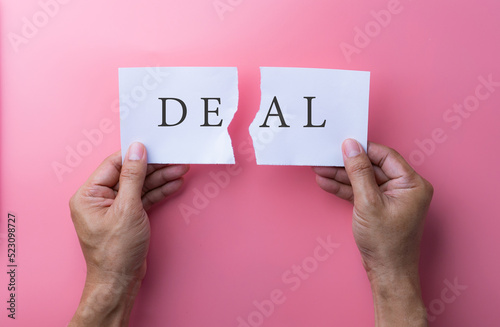 Business deal or transaction concept with the word - Deal - split over two pages of paper on different clipboards with businessmen shaking hands above them photo