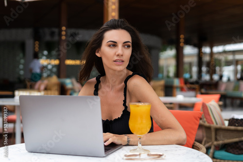 Beautiful young female freelancer working with a laptop in a street cafe