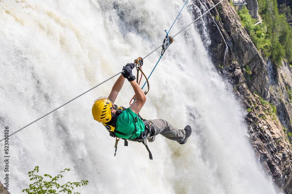 Man on a zipline going past a waterfall Man on a zipline going past a waterfall
