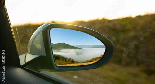 The view of the mountains in the car's rearview mirror.