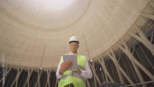 Engineer working inside Cooling tower in power plant.
The engineer works with his tablet in the cooling tower inside the nuclear power plant.
