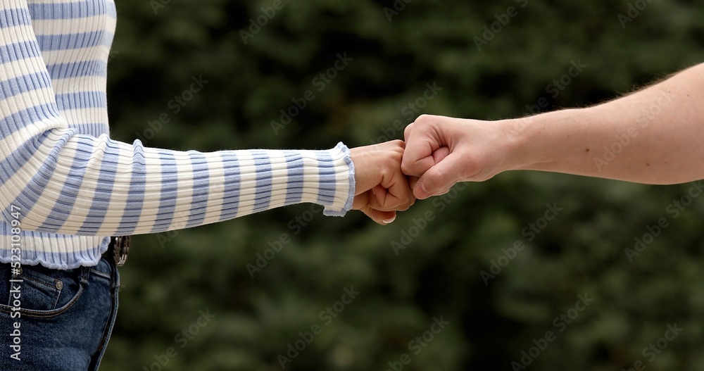 A close up image of a fist bump man and woman outdoor. Friendship concept. A close up image of a fist bump man and woman outdoor. Friendship concept.
