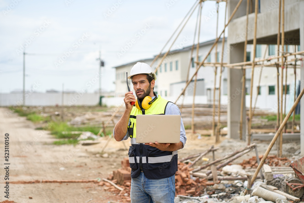 Foreman order to team with walkie talkie by spec on laptop on construction site