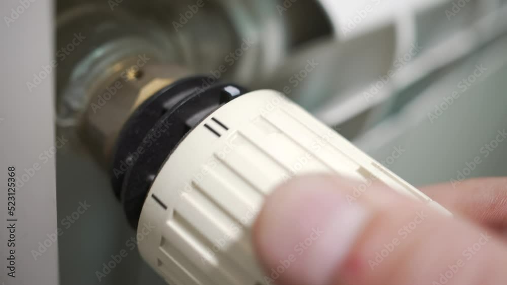 Person turns a heater on and off on a thermostat. Energy saving. Close-up. Person turns a heater on and off on a thermostat. Energy saving. Close-up.