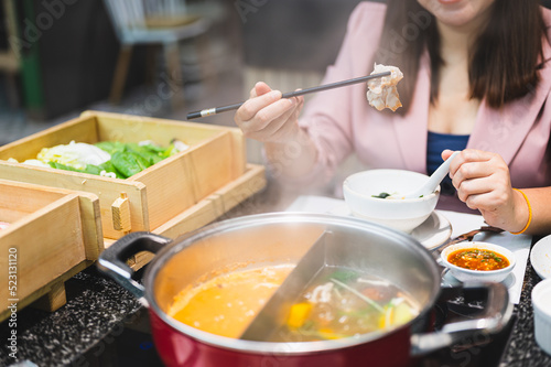 Asian woman using chopsticks to put food into her mouth