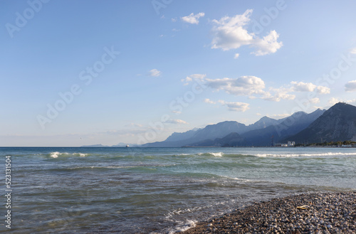 Pebble beach with cloudy blue sky on foggy mountains background
