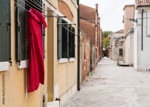 Red garment hung to dry outside a window in Venice, Italy