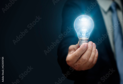Close-up of businessman holding a light bulb with brain inside ,creative innovation ideas ,learning new things for corporate development inspiration ,science and communication technology concept