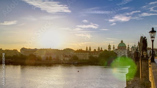 View from Charles Bridge in Prague during the sunrise timelapse, Bohemia, Czech Republic. Cloudy sky, reflection in Ltava river photo