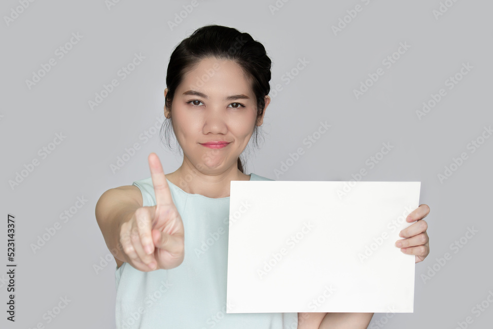 Asian beautiful woman raise pointing finger gesture hand sign to prohibit and warning and holding white paper or board for writing text or information to communicate to people Asian beautiful woman raise pointing finger gesture hand sign to prohibit and warning and holding white paper or board for writing text or information to communicate to people