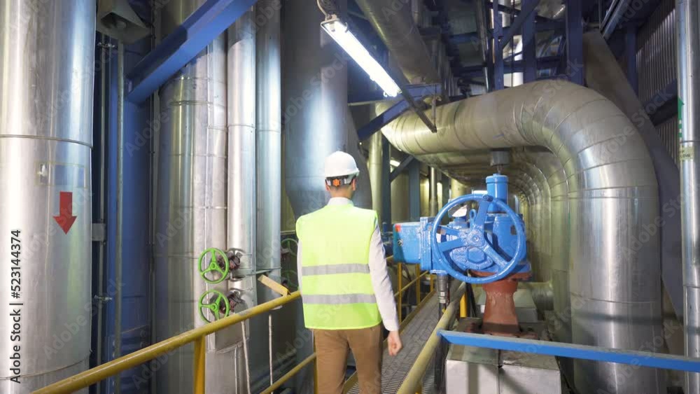 In the industrial factory, the engineer turns the valve. The engineer