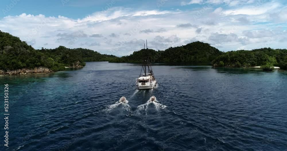Aerial shot of diving boat going along tropical island with shallow reef Aerial shot of diving boat going along tropical island with shallow reef