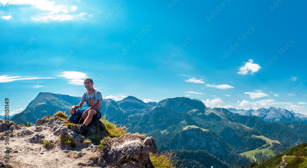 A happy Man is Hiking in the alps. Relaxing, resting on a Stone. Jenner Mountain - Berchtesgaden Alps, Germany