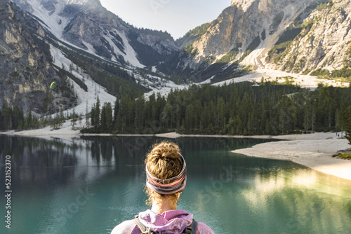 Young woman enjoys amazing view on Braies Lake in Dolomites mountains in the morning. Braies Lake (Pragser Wildsee, Lago di Braies), Dolomites, South Tirol, Italy, Europe.