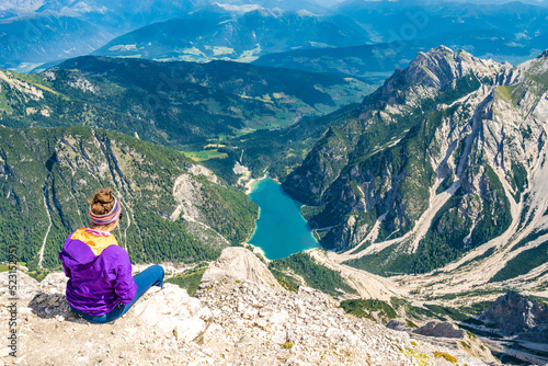 Young woman enjoys beautiful view from Seekofel on Braies Lake in the Dolomite mountains at noon. Seekofel, Dolomites, South Tirol, Italy, Europe.