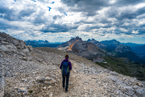 Young woman is hiking on beautiful trail Seekofel to Baires Lake in the Dolomite mountains in the afternoonSeekofel , Dolomites, South Tirol, Italy, Europe.