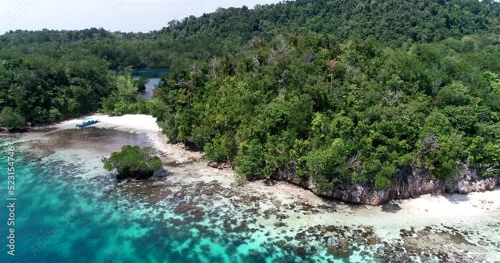 Aerial shot of tiny sailing boat along tropical island with shallow reef Aerial shot of tiny sailing boat along tropical island with shallow reef