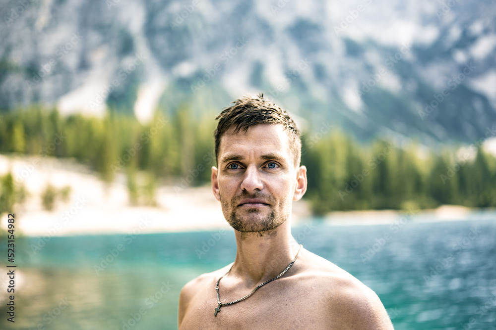 Young shirtless man with visionary view at Baires Lake in the Dolomite mountains in the afternoon. Braies Lake (Pragser Wildsee, Lago di Braies), Dolomites, South Tirol, Italy, Europe.