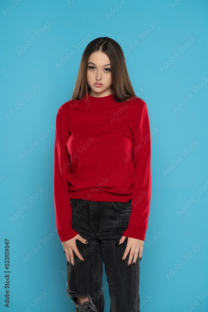 Cute girl in red blouse and black jeans isolated on blue background Cute girl in red blouse and black jeans isolated on blue background