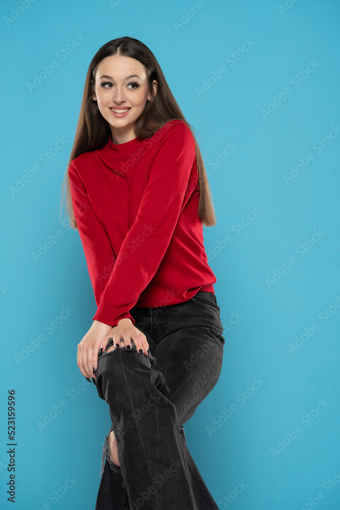 Cute smiling girl in red blouse and black jeans isolated on blue background Cute smiling girl in red blouse and black jeans isolated on blue background