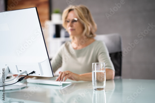 Water Drinking Glass On Desk And Woman In Foreground