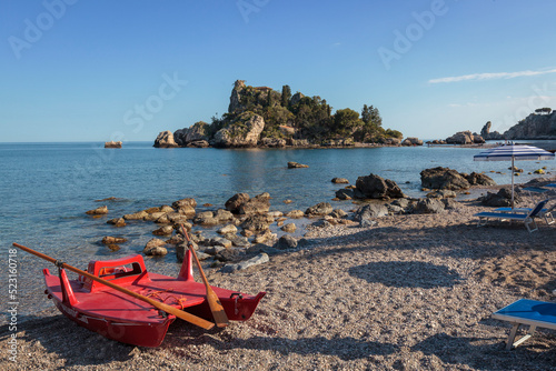 Acitrezza, Catania. Spiaggia con barca verso l'isola di Aci castello photo