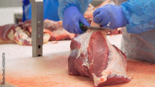 Butcher cutting beef by the conveyor belt