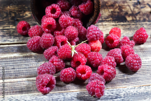 Raspberries in a wooden glass on a wooden background