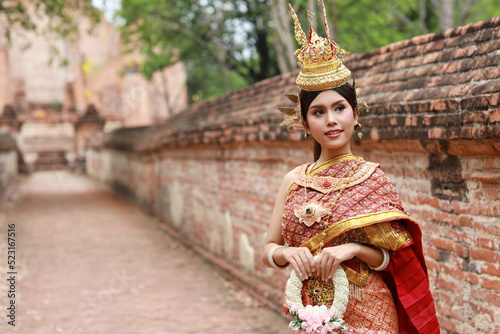 Young fashion and beautiful asian woman wearing Thai red traditional costume holding jasmine flower garland with happy and peace standing outdoor in ancient temple Ayutthaya, Thailand. Travel concept © feeling lucky