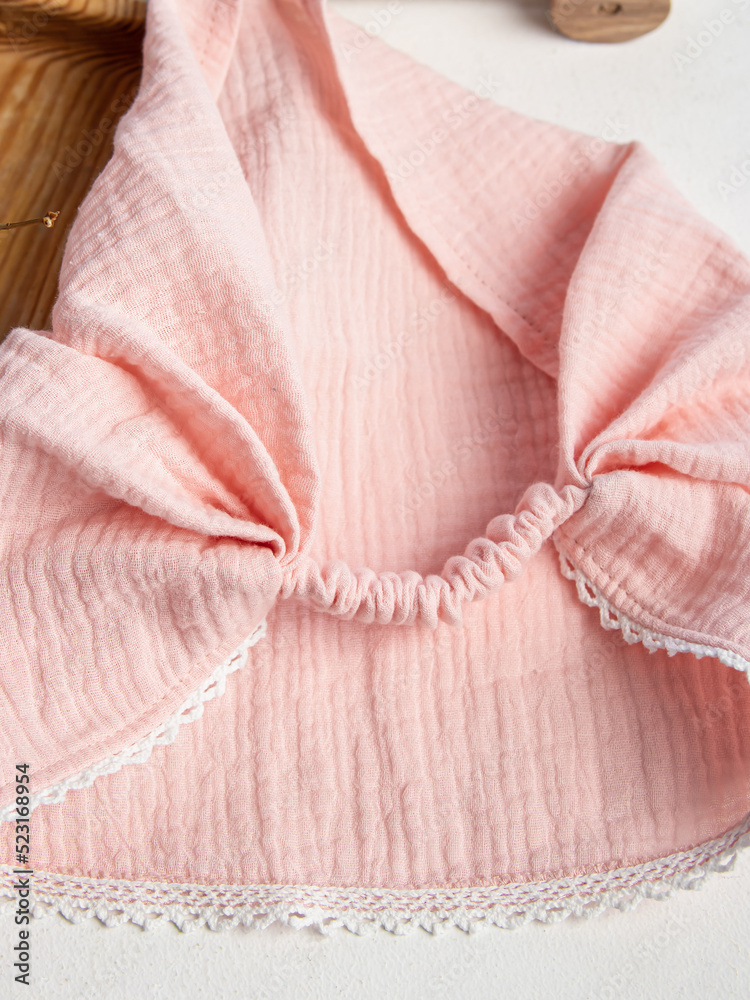 Pink children's summer scarf on white background. Muslin headdress. Scarf with elastic band. Closeup