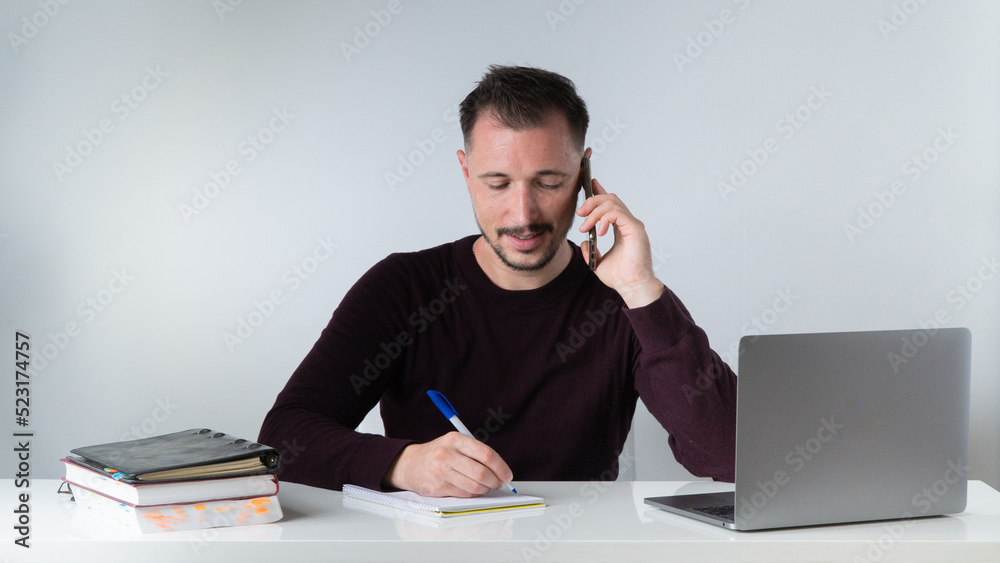 A man works in an office with a laptop, documents and talks on the phone A man works in an office with a laptop, documents and talks on the phone