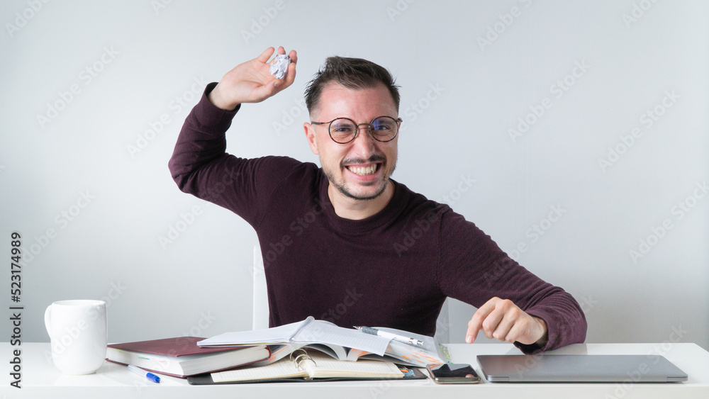 An angry employee throws crumpled paper at his desk An angry employee throws crumpled paper at his desk