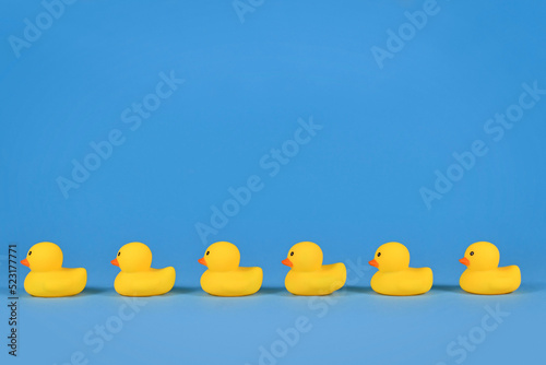 Yellow rubber ducks in a row on blue background with copy space