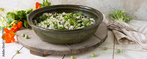 dish with risotto with spinach, green peas and broccoli on a light table