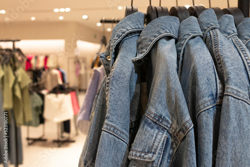 Female denim jackets on hangers. Defocused store background. Fashion concept.