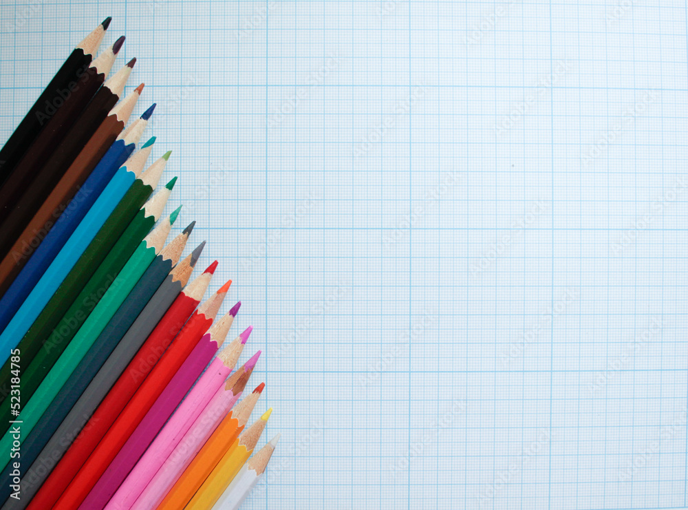 Colored pencils on a plotting paper, top right view with space for text. Back to school concept copy space for text. Colored pencils on a plotting paper, top right view with space for text. Back to school concept copy space for text.