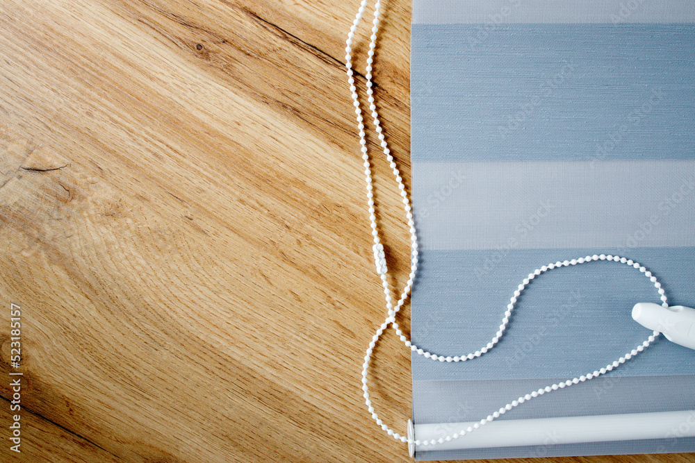 A sample of the finished fabric blind of the day and night system on a wooden background, copy space