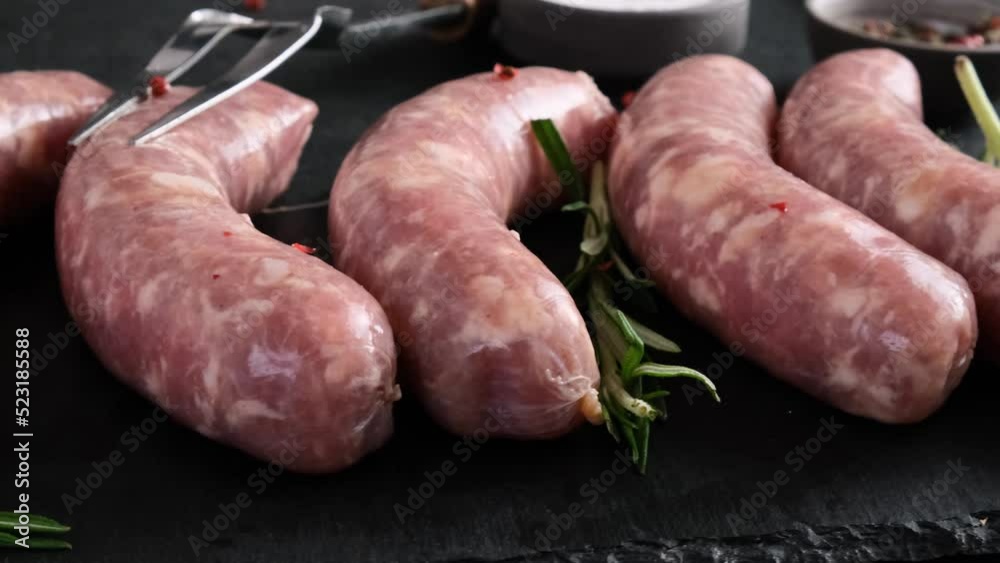 Raw pork sausages or bratwurst for grill or barbecue ready for cooking on Oktoberfest on black background. Close up. 4k video Raw pork sausages or bratwurst for grill or barbecue ready for cooking on Oktoberfest on black background. Close up. 4k video