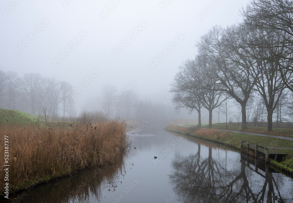 valleikanaal or valley canal near scherpenzeel in the netherlands on misty winter day