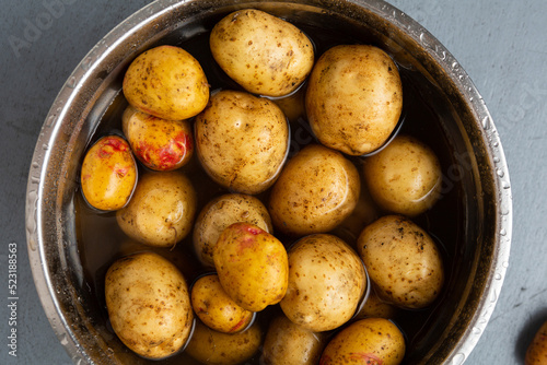 Top view of raw potaoes roots in bowl with water cooking concept photo