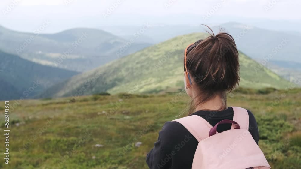Young brunette woman standing on a peak of rock and looking at the mountains landscape Young brunette woman standing on a peak of rock and looking at the mountains landscape